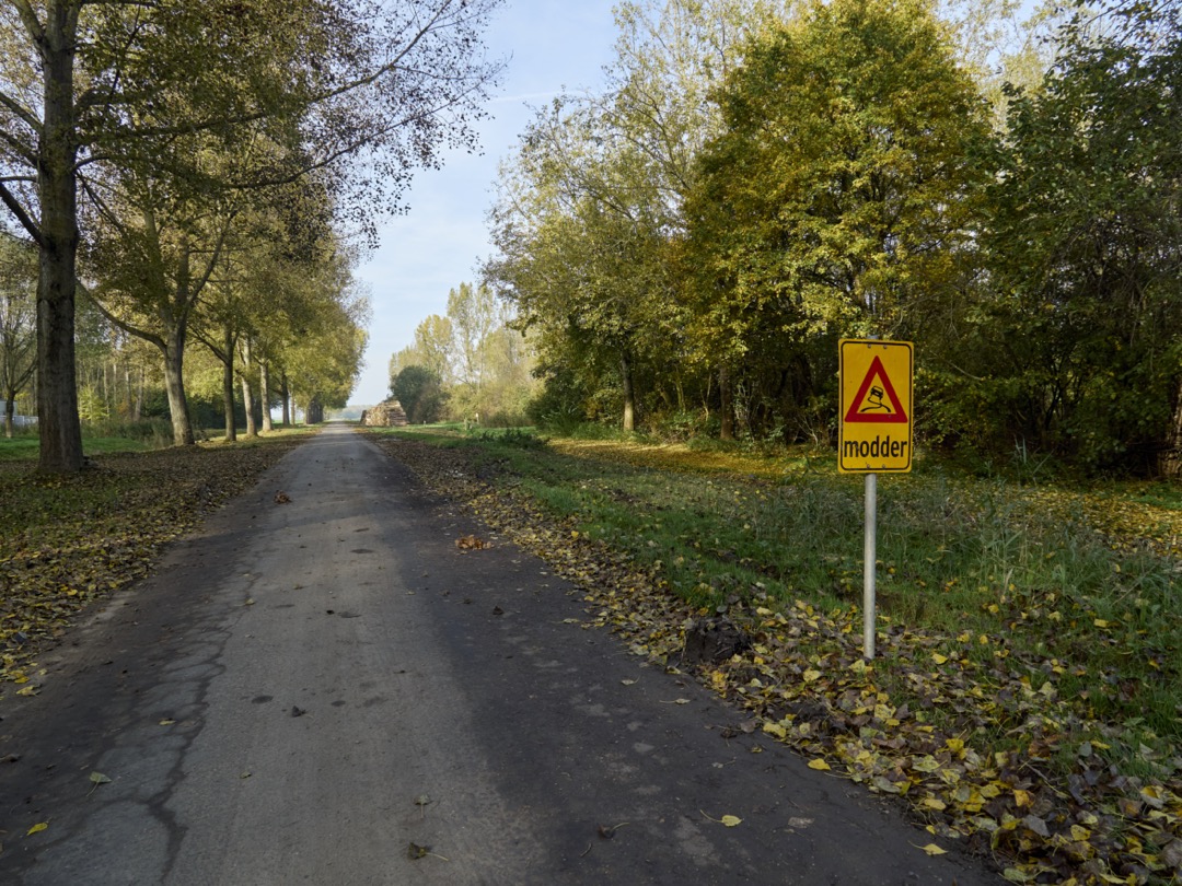 Foto van de Brikweg in Almere Pampus met een bord waarop het woord modder staat