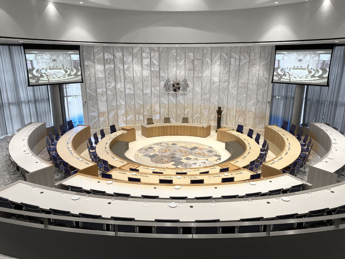 Foto van de raadzaal met de raadzetels in volle kleuren en de rest met weinig kleur